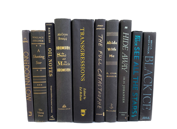 Black foil lettered black decorative books. Color-coded book stack by the shelf foot.