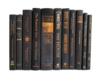 Copper and gold foil lettered black decorative books. Color-coded book stack by the shelf foot