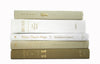 White, tan and beige neutral decorator books. Color-coded book stack by the shelf foot
