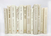 foiled lettered beige decorator books. Color-coded book stack by the shelf foot. 